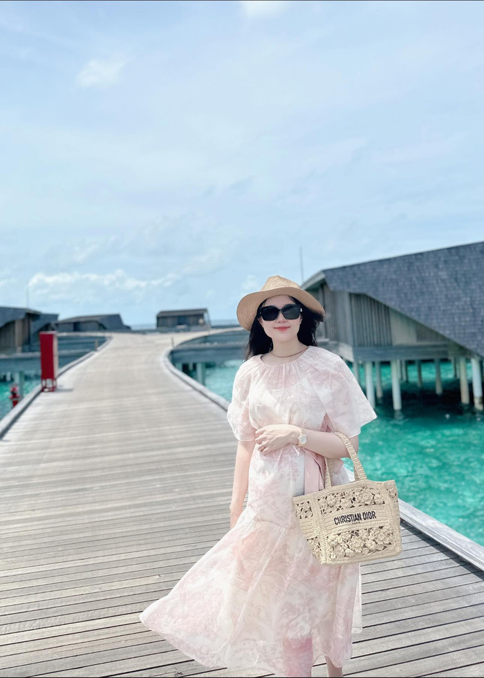 Thời trang đi du lịch biển của Quỳnh Anh cũng được công chúng hết lời khen ngợi. Thay vì diện những mẫu bikini 'cắt xẻ' khoe da thịt, vợ Duy Mạnh theo đuổi phong cách nàng thơ, ngọt ngào trong bộ váy mang tông màu hồng pastel. Về phụ kiện, cô phối cùng nón cói, kính mát đen cùng mẫu túi xách đến từ 'nhà mốt' đến từ Pháp, được bán với mức giá 140 triệu đồng.