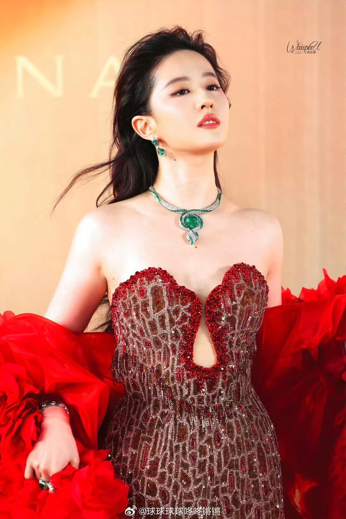 Lưu Diệc Phi trở thành tâm điểm sự kiện khi xuất hiện trong mẫu váy đồ sộ nhuộm tông đỏ quyền lực. Sở hữu số đo ba vòng chuẩn cùng lợi thế chiều cao, ngôi sao phim Câu chuyện hoa hồng dễ dàng chinh phục thiết kế cúp cung có đường may ôm sát. Tăng thêm điểm cho vẻ ngoài diễm lệ, nhà mốt Tony Ward đã ướm thêm chiếc áo choàng cách điệu mang hình ảnh hàng trăm đóa hoa đang vươn mình khoe sắc cho mẫu Haute Couture.  