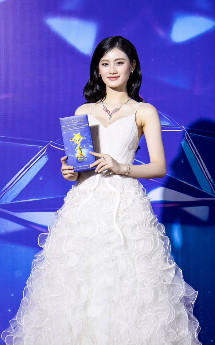 Hoa hậu Ý Nhi trông y hệt một nàng công chúa khi diện bộ váy dạ hội trắng, phần thân được đính kết từ nhiều lớp, tạo hiệu ứng bồng bềnh đẹp mắt. Ý Nhi trang điểm nhẹ nhàng, khoe ngũ quan hài hoà, khí chất ấn tượng trước thềm chinh chiến quốc tế. Để 'outfit' thêm phần đặc biệt, Ý Nhi còn kết hợp thêm bộ trang sức màu trắng bạc, đính đá. Trên các diễn đàn, Ý Nhi được khen ngày một thăng hạng nhan sắc.