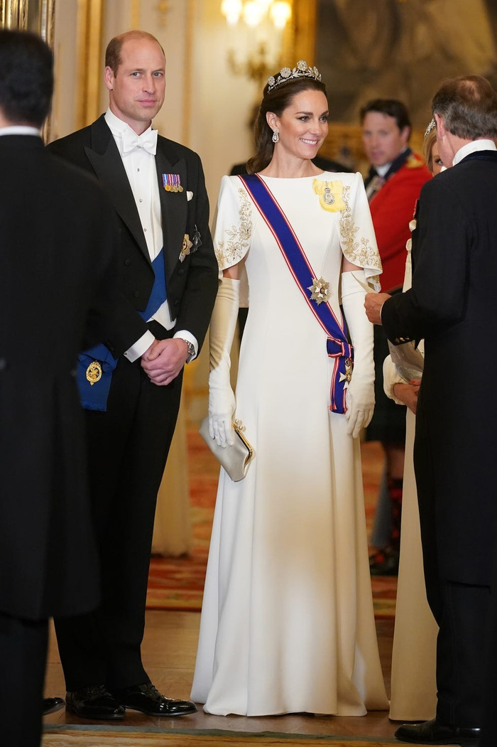 Trong bữa tiệc cấp nhà nước tại Cung điện Buckingham, Công nương Kate xuất hiện với vẻ đẹp lộng lẫy trong chiếc váy dài màu trắng của Jenny Packham, kết hợp cùng vương miện hoa hồng Strathmore mang đậm tính biểu tượng hoàng gia.