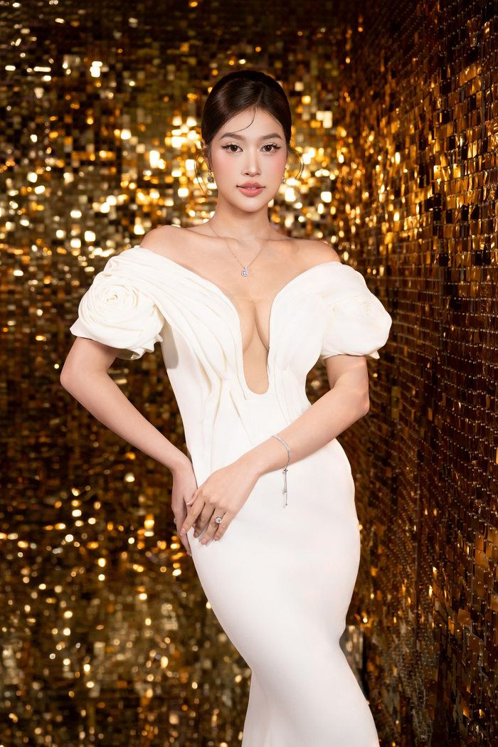 Người đẹp tinh tế lựa chọn mẫu đàm có phần vai trễ kết hợp chi tiết tay bồng mang đến vẻ nữ tính, nhẹ nhàng, đồng thời tạo điểm nhấn sang trọng. Đường cắt cổ chữ V sâu giúp kéo dài phần cổ của Hoa hậu Thiên Ân, tạo vẻ quyến rũ nhưng không phô trương. Trang phục giúp Miss Grand Vietnam 2022 tạo cảm giác thanh lịch và làm nổi bật làn da mịn màng. 