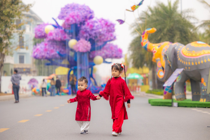 2 em bé được bố mẹ sắm cho những bộ áo dài đỏ càng làm tưng bừng không khí Tết