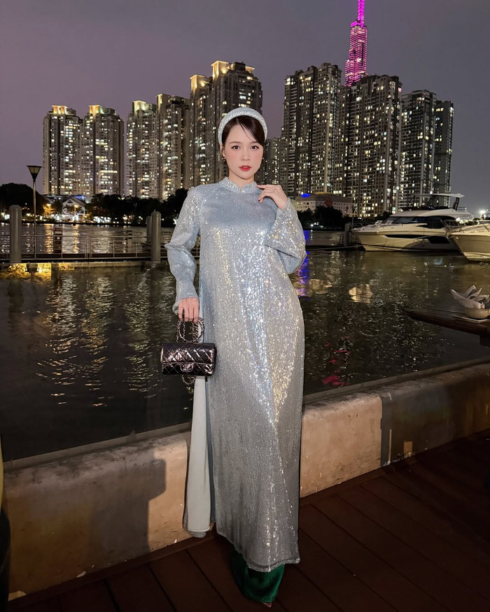 Sam diện mẫu áo dài truyền thống với chất liệu sequin nổi bật. Thiết kế này giúp tôn lên làn da trắng sáng, không chút khuyết điểm của bà mẹ 2 con. Về phụ kiện, Sam phối cùng băng đô cài tóc đồng màu và chiếc túi xách nắp gập đến từ 'nhà mốt' xa xỉ tại Pháp, được bán với mức giá lên đến hàng trăm triệu đồng. (Ảnh: FBNV)