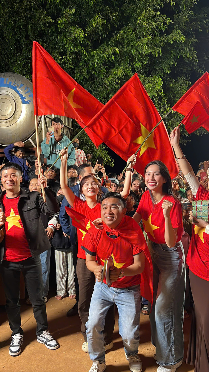 Quang Linh và Hoa hậu Thùy Tiên diện áo màu cờ Việt Nam xem trận chung kết lượt đi của Việt Nam và Thái Lan ở ASEAN CUP 2024.