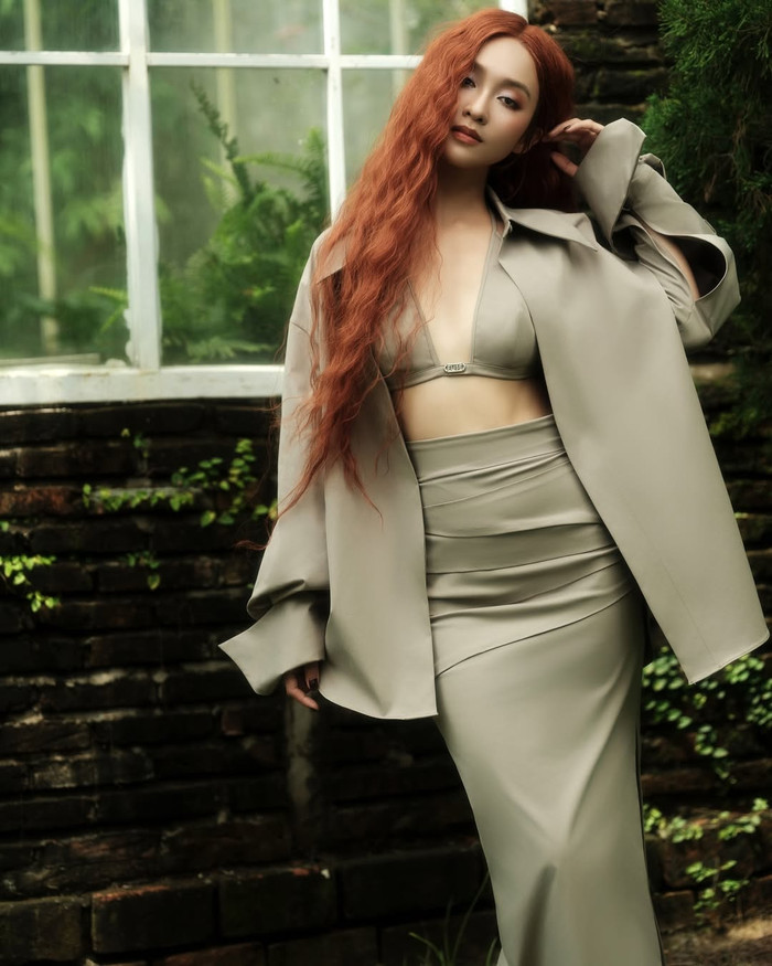 Vẫn thiết kế áo bra nhỏ xíu quen thuộc đó nhưng Khả Ngân lại chọn phối cùng với chân váy chữ A cùng áo blazer dáng dài, tạo cảm giác mới lạ. Bản phối này phần nào tiết chế đi sự quyến rũ nhưng vẫn đủ để nữ diễn viên tôn lên ưu điểm về hình thể. Để tăng thêm độ nổi bật, Khả Ngân 'chơi lớn' khi nhuộm mái tóc thành màu đỏ cam và dập tóc gợn sóng. (Ảnh: FBNV)