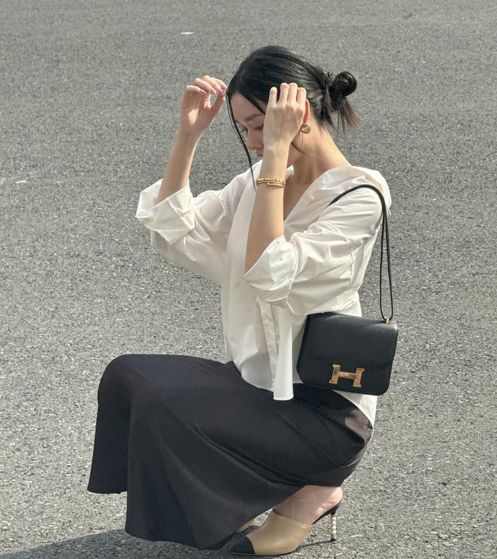 Á hậu Tường San còn 'kết thân' với những mẫu túi hiệu mang tông màu đen, chất liệu da và thiết kế khá đơn giản, không có nhiều hoạ tiết. Trong hình ảnh trên, Á hậu Tường San sử dụng mẫu túi xách trị giá khoảng 16.000 USD (hơn 400 triệu đồng) kết hợp cùng bản phối thời trang thanh lịch gồm áo sơ mi và chân váy dáng dài. (Ảnh: FBNV)