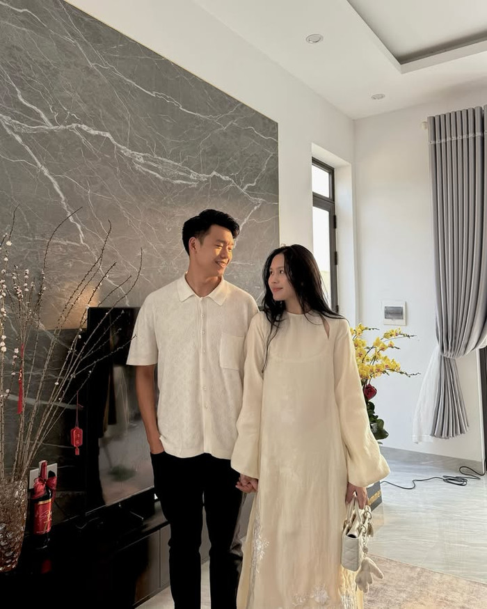 Vợ chồng Thành Chung đều cho thấy sự ăn ý trong việc lựa chọn trang phục. Cặp đôi đều 'lên đồ' đồng điệu về màu sắc. Ở mùng 1 Tết, Thành Chung - Tố Uyên diện áo dài đỏ rực rỡ và thu hút. Đến mùng 2 Tết chỉ còn mỗi vợ Thành Chung tiếp tục chọn trang phục này nhưng ở phiên bản màu trắng tinh khôi. Tuy nhiên, Thành Chung vẫn khéo léo 'kết thân' với chiếc áo thun màu đồng màu với trang phục của vợ. (Ảnh: FBNV)