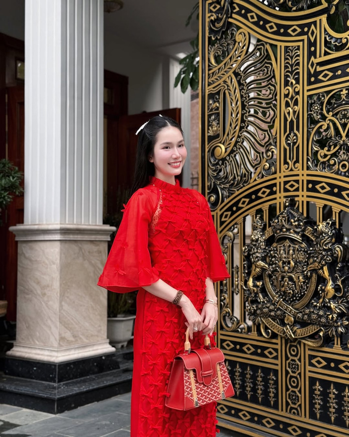 Á hậu Phương Anh diện áo dài đỏ rực, được đính kết bằng họa tiết nơ xếp lớp, tạo độ bắt mắt. Không những vậy, nàng hậu còn phối cùng chiếc túi xách cỡ lớn, có màu sắc đồng bộ với trang phục. Món phụ kiện này có giá trị khoảng 150 triệu đồng. (Ảnh: FBNV)