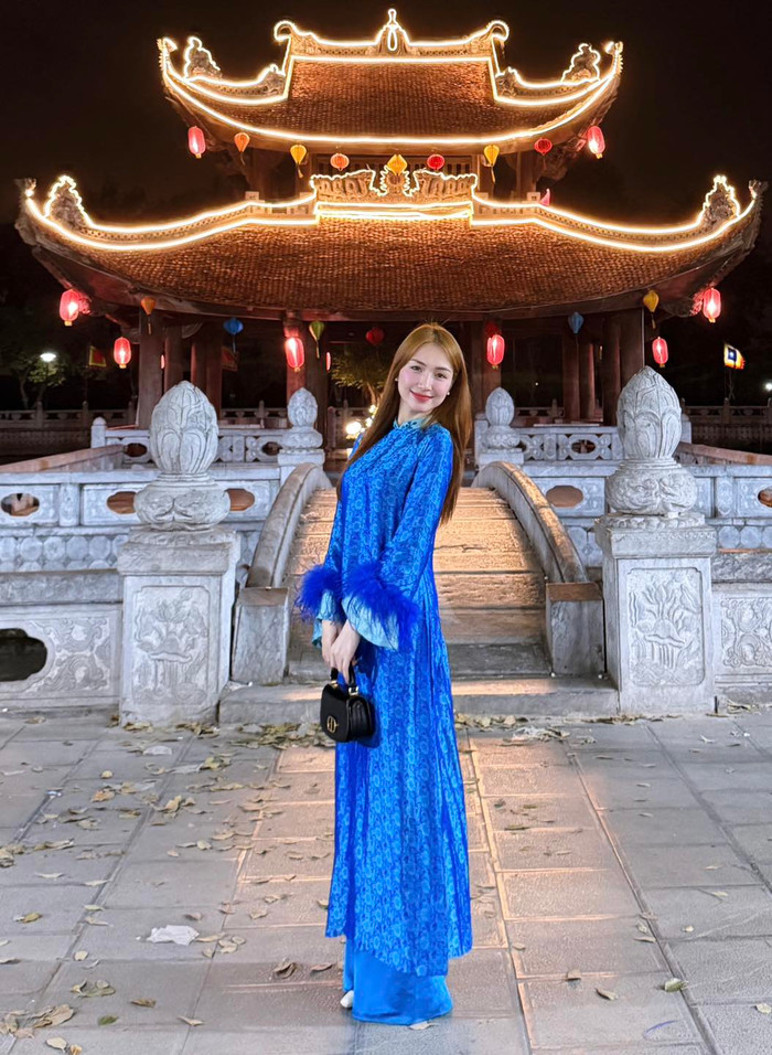 Đi chơi ngày mùng 2 Tết Nguyên Đán 2025, Hòa Minzy khoác lên người mẫu áo dài truyền thống, mang tông màu xanh nước biển mát mắt. Thiết kế này còn được tạo điểm nhấn bằng chi tiết lông vũ ngay phần cổ tay, toát lên vẻ sang trọng, quý phái. Để tăng thêm phần 'chanh xả', Hòa Minzy phối cùng mẫu túi xách hàng hiệu đến từ 'nhà mốt' có Jisoo làm đại sứ toàn cầu. Món phụ kiện này được bán với mức giá khoảng 89 triệu đồng. (Ảnh: FBNV)