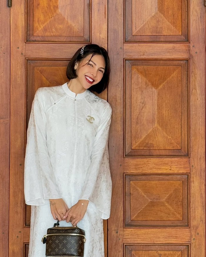 Minh Triệu diện mẫu áo dài trắng tinh khôi, khoe khéo nhan sắc tươi tắn và rạng rỡ. Về phụ kiện, nữ siêu mẫu phối cùng chiếc túi xách họa tiết monogram đến từ 'nhà mốt' xa xỉ của Pháp. Thiết kế này được bán với mức giá niêm yết khoảng 75,5 triệu đồng. (Ảnh: FBNV)