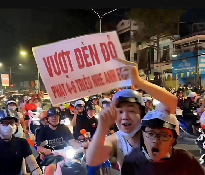 Tấm bảng 'Vượt đèn đỏ phạt 4-6 triệu' như một lời nhắc nhở mọi người đi 'bão' cũng phải chấp hành an toàn giao thông.