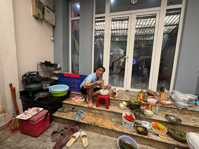 MC Quyền Linh ăn mì gói ngay trước thềm nhà. (Ảnh FBNV)