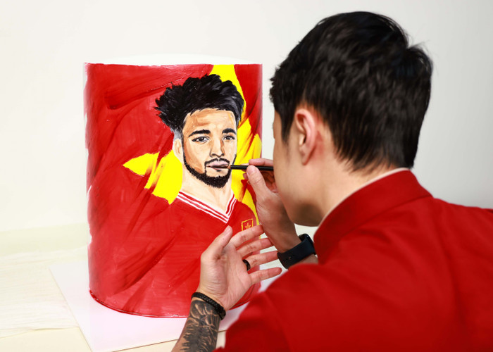 Nghệ nhân làm bánh tỉ mỉ vẽ hình ảnh cầu thủ Nguyễn Xuân Son lên bánh. Ảnh: NVCC