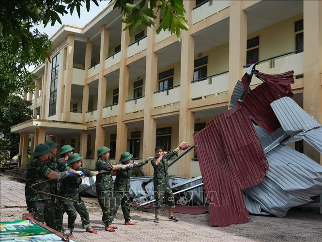 Lực lượng chức năng hỗ trợ các trường học khắc phục sau mưa bão. Ảnh: TTXVN-VNA
