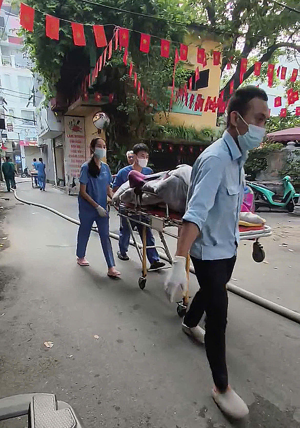 Những thi thể cuối cùng được bọc kín trong chăn, lần lượt được đưa ra khỏi hiện trường lúc 7h sáng. Đây là hình ảnh đau lòng nhất, là kết cục của cả một gia đình gồm ông bà ngoài 60, vợ chồng trung niên và cháu nội mới 6 tuổi. (Ảnh: VnExpress)