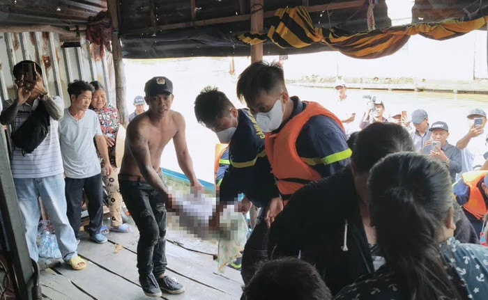 Lực lượng chức năng đưa thi thể cháu bé lên bờ. Ảnh: báo An Giang