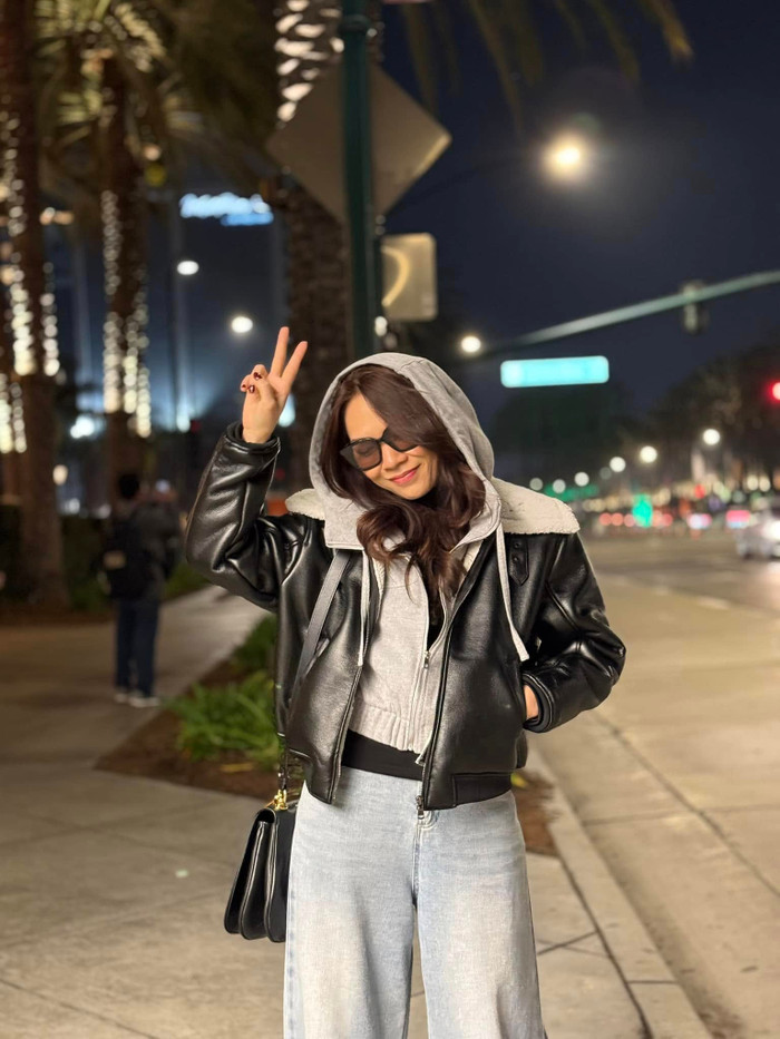 Phong cách của nữ ca sĩ cũng nổi bật nhờ kỹ thuật layering (phối lớp) thông minh và cách sử dụng phụ kiện tinh tế. Khi ra phố buổi tối, cô kết hợp áo khoác da cá tính với hoodie có mũ bên trong và quần jeans ống rộng, tạo nên tổng thể thời thượng, chuẩn phong cách street style. Ảnh: FBNV