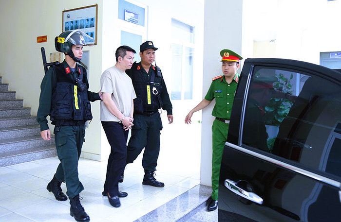 Dẫn giải bị can Nguyễn Quốc Vũ. (Nguồn: Công an nhân dân) 