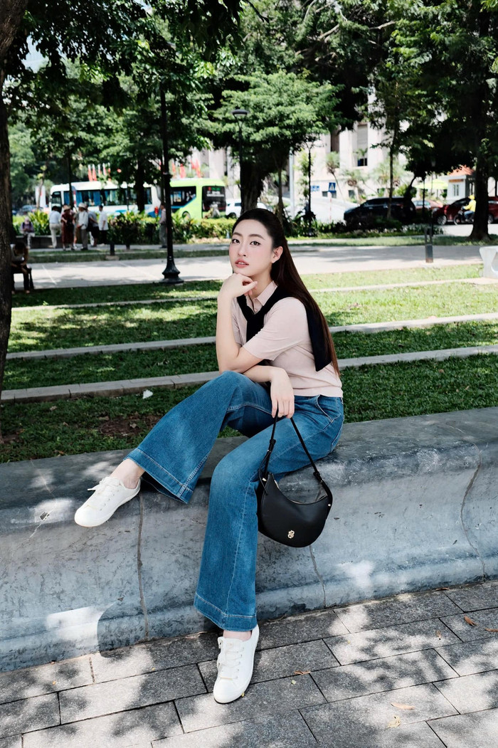 Lương Thùy Linh cũng thể hiện sự linh hoạt trong cách phối đồ để phù hợp với từng bối cảnh xuất hiện. Khi dạo phố hay đến các quán cà phê, cô ưu tiên sự thoải mái, năng động với công thức kinh điển của Gen Z: quần jeans ống loe kết hợp áo phông cơ bản và giày sneakers. Ảnh: FBNV