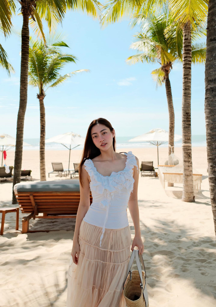 Trong các chuyến du lịch nghỉ dưỡng, nàng hậu lại trở nên dịu dàng, lãng mạn hơn với các set đồ bay bổng, nữ tính như váy maxi dài tông màu vàng kem hay chân váy midi xếp tầng. Ảnh: FBNV