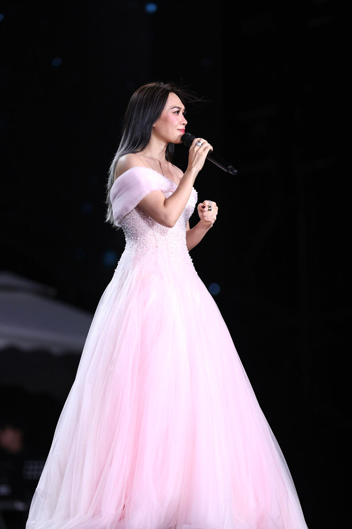 Một điểm nhấn khác là chiếc đầm hồng phớt off-shoulder đính ngọc trai và lớp tulle đa tầng. Phần vai trần tinh tế kết hợp thân trên phủ ngọc trai dày đặc, chuyển xuống chân váy tulle bồng bềnh. Chất liệu nhẹ giúp Mỹ Tâm uyển chuyển trong các ca khúc ballad, đồng thời hiệu ứng lấp lánh từ ngọc trai làm nổi bật vẻ kiêu sa dưới ánh sáng sân khấu. Ảnh: FBNV