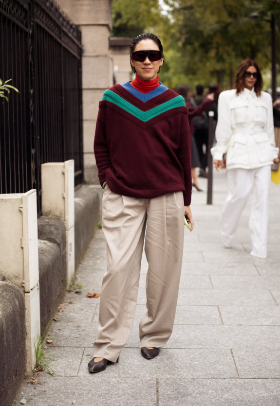 Hướng đến những món đồ chuẩn phong cách preppy, một chiếc áo len cổ lọ đỏ tươi phối bên trong áo len sọc mang cảm hứng rugby tạo điểm nhấn nổi bật. Khi kết hợp cùng quần kaki xếp ly và phụ kiện hiện đại như giày bệt dạng găng tay hay túi xách vai, set đồ này hoàn hảo hòa trộn tinh thần cổ điển của đồng phục varsity với xu hướng thời trang đương đại. Ảnh: Harpers Bazaar