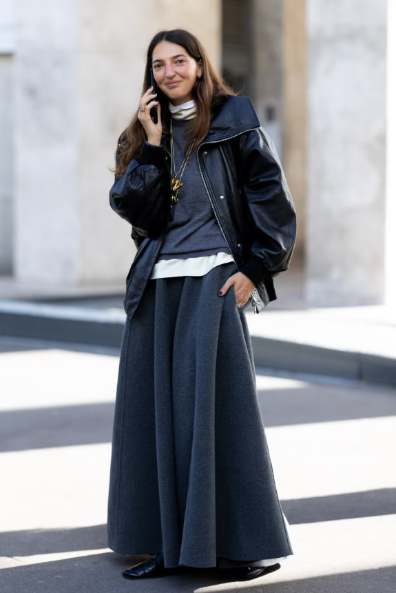 Kết hợp nhiều kiểu cổ áo khác nhau với áo len cổ lọ tạo chiều sâu cho trang phục, đồng thời chọn màu sắc đối lập để tránh cảm giác đơn điệu. Một chiếc áo màu kem bên trong áo crewneck xám mang lại vẻ tươi mới, đặc biệt khi phối cùng áo bomber da, chân váy A-line chất liệu len và boots mũi nhọn. Ảnh: Harpers Bazaar