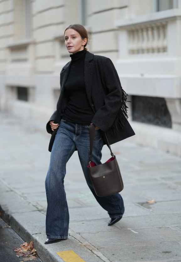 Nếu không muốn quá cầu kỳ khi phối layer, hãy chọn một chiếc áo len cổ lọ dày làm tâm điểm cho trang phục, sau đó khoác thêm một chiếc áo khoác trendy bên ngoài, như phiên bản tua rua. Chất liệu của áo khoác da lộn đen và áo len cashmere tạo sự hài hòa, mang lại chiều sâu cho những món đồ cơ bản mùa đông như jeans tối màu và boots da. Ảnh: Harpers Bazaar