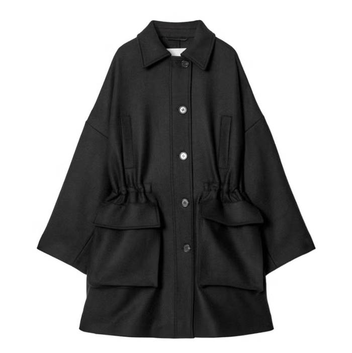 Chiếc áo khoác Cos Manteau Workwear bằng len màu đen nổi bật với eo thắt nhẹ và túi bản to, mang đến vẻ năng động, tiện dụng. Thiết kế dáng dài đến đầu gối càng tăng thêm sự linh hoạt, phù hợp cho nhiều phong cách khác nhau. Ảnh: Harpers Bazaar
