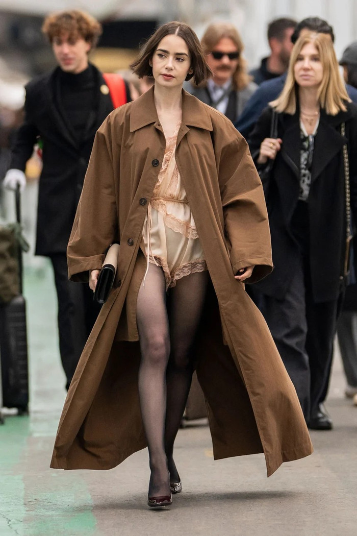 Lily Collins khoác thêm một chiếc áo khoác dáng dài đến mắt cá chân ngoài bộ jumpsuit. Ảnh: Shutterstock