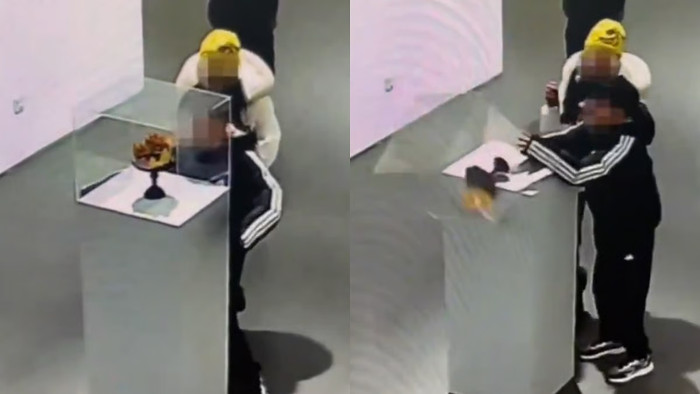 Cậu bé lau chùi tủ kính trưng bày trong khi mẹ cậu quan sát. Vài giây sau, chiếc tủ kính đổ sập xuống. Ảnh: Douyin