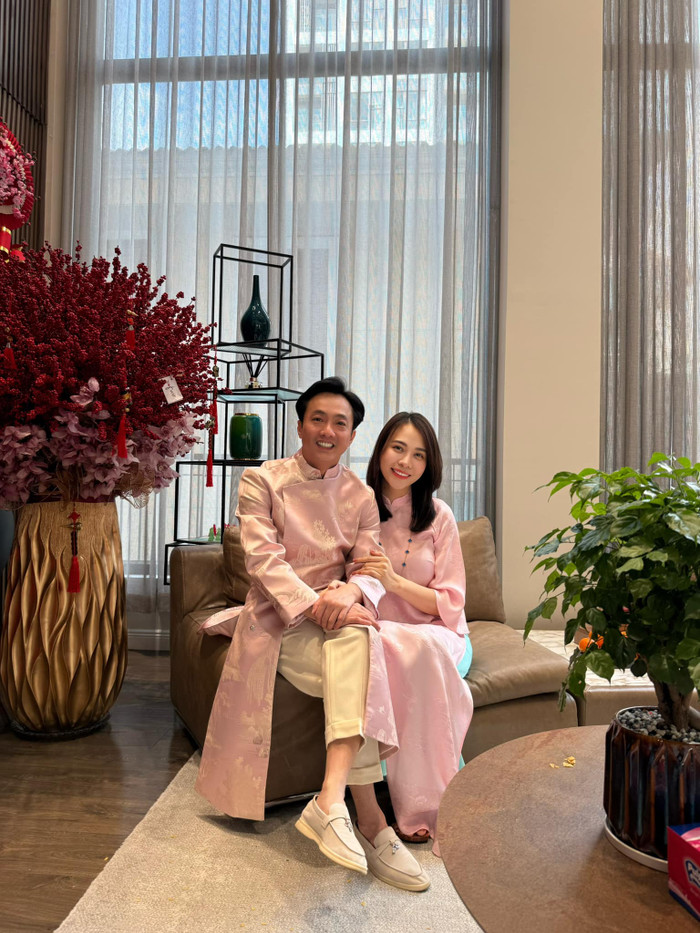 Ở những khoảnh khắc mang không khí truyền thống, cặp đôi cùng lựa chọn áo dài hồng phấn với phom dáng thanh lịch, chất liệu cao cấp. Đàm Thu Trang toát lên vẻ đài các, dịu dàng, trong khi Cường Đô La ghi điểm bởi nét lịch lãm, phong độ, tạo nên tổng thể hài hòa, ấm áp nhưng vẫn hiện đại.