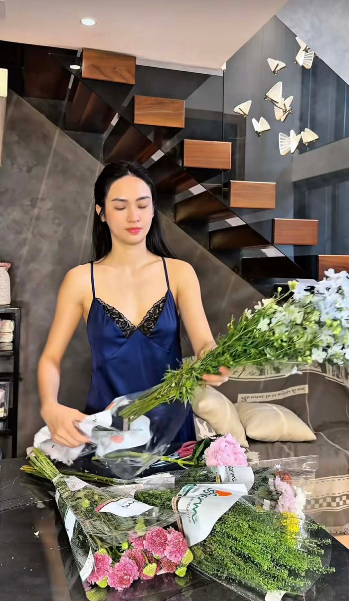 Trong khi đó, bộ váy lụa xanh navy lại mang đến sự sang trọng, sâu lắng hơn với kiểu dáng chữ V sâu, chất liệu lụa cao cấp phản chiếu ánh sáng nhẹ nhàng. Tuy nhiên đây cũng là mẫu váy gây nhiều tranh cãi, khi một số ý kiến cho rằng trang phục không phù hợp để quay video cắm hoa. Ảnh chụp màn hình