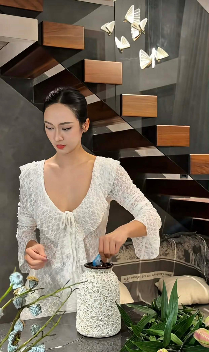 Chuyển sang các khoảnh khắc khác, Thúy Quỳnh lựa chọn phong cách tối giản hơn nhưng vẫn đầy sức hút. Bộ váy ren trắng dài tay, cổ tròn sâu, form suông nhẹ nhàng ôm lấy cơ thể, được làm từ chất liệu ren cao cấp với họa tiết lỗ thoáng khí. Thiết kế này tạo cảm giác thanh lịch, phù hợp với hoạt động cắm hoa đòi hỏi sự khéo léo của đôi tay. Lớp ren dày dặn ở phần thân trên kết hợp với độ dài tay áo giúp Thúy Quỳnh vừa thoải mái di chuyển, vừa giữ được vẻ thanh lịch cần thiết. Ảnh chụp màn hình