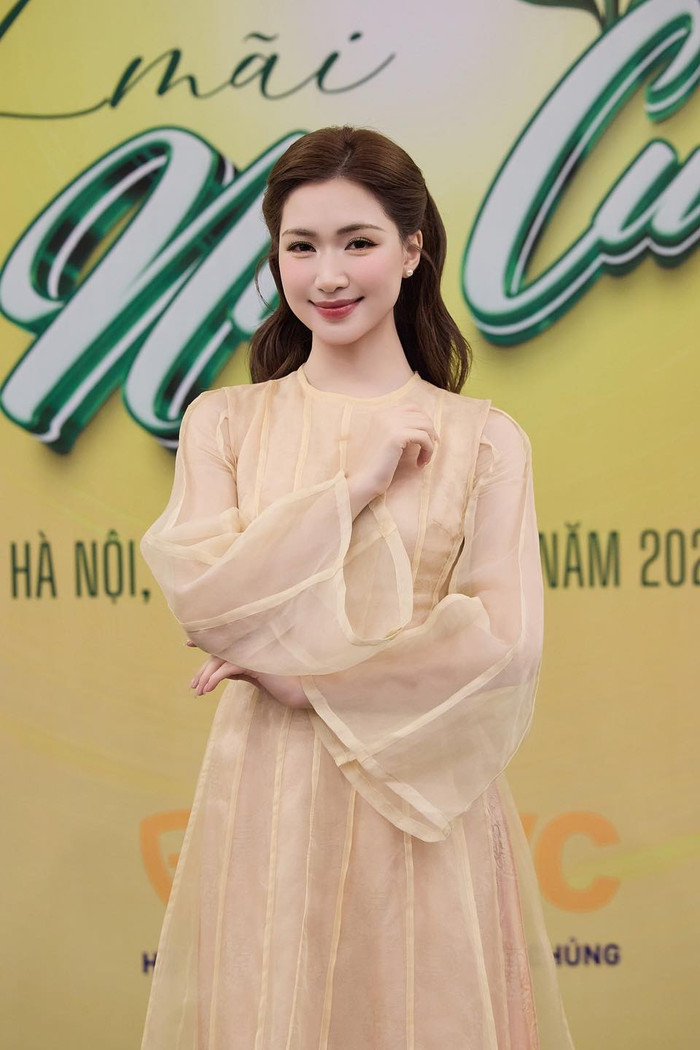Tại một sự kiện ở Hà Nội, Hòa Minzy xuất hiện trong chiếc áo dài màu kem nhạt làm từ chất liệu voan mỏng nhẹ, lớp lớp xếp tầng tạo hiệu ứng bay bổng, nhẹ nhàng. Thiết kế giữ nguyên phom dáng cổ điển với cổ tròn thanh lịch, tay dài và tà áo dài chấm gót, mang đến cảm giác dịu dàng, kín đáo phù hợp với không gian sự kiện văn hóa. Ảnh: FBNV