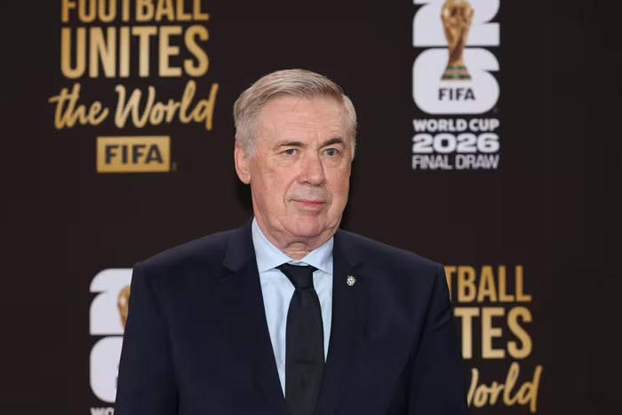 Carlo Ancelotti xuất hiện trên thảm đỏ World Cup 2026 với bộ suit navy cổ điển, kết hợp áo sơ mi trắng và cà vạt đen. Bộ suit được cắt may ôm sát, chất liệu len cao cấp tạo độ bóng nhẹ, tôn dáng vóc chắc khỏe của vị HLV kỳ cựu. Chi tiết huy hiệu nhỏ trên ve áo là điểm nhấn tinh tế, thường thấy ở các thiết kế suit bespoke từ thương hiệu Ý như Armani hay Zegna. Phong cách này phản ánh gu thời trang tối giản nhưng sang trọng mà Ancelotti duy trì suốt sự nghiệp. Ảnh: FIFA