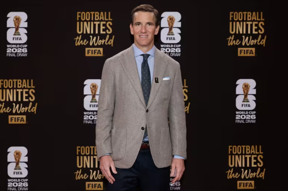 Eli Manning, cựu quarterback huyền thoại của New York Giants, đã góp mặt tại sự kiện bốc thăm vòng chung kết World Cup 2026, với vai trò dẫn chương trình thảm đỏ. Bộ suit Ralph Lauren Purple Label mà anh chọn nổi bật với form dáng slim-fit hiện đại, ve áo notch lapel rộng vừa phải tạo chiều sâu vai. Cách phối hợp này của thể hiện sự chú trọng đến chi tiết, tạo lớp nền hoàn hảo cho hình ảnh dẫn chương trình chuyên nghiệp. Ảnh: FIFA