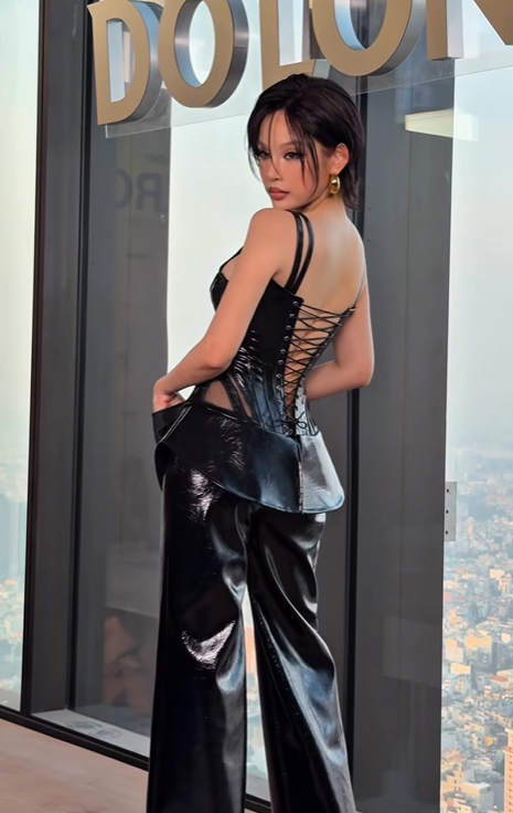 Huyền Baby diện set đồ đen đầy cá tính với thiết kế corset da bóng kết hợp chất liệu lưới xuyên thấu, tạo điểm nhấn gợi cảm và tôn vòng eo thon. Găng tay đen, khuyên tai vàng và layout trang điểm sắc nét giúp tổng thể thêm phần thời thượng, cho thấy phong cách thời trang ngày càng táo bạo và cuốn hút của người đẹp. Ảnh: FBNV