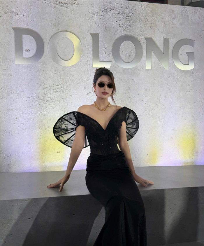 Hoa hậu Đoàn Thiên Ân chọn thiết kế đầm đen ôm dáng với phần vai dựng phom bằng ren tạo hiệu ứng thị giác mạnh mẽ. Chi tiết thắt eo và chất liệu xuyên thấu được xử lý tinh tế giúp tổng thể vừa gợi cảm vừa sang trọng. Việc kết hợp kính mắt nhỏ thời thượng cùng vòng cổ kim loại bản lớn càng làm nổi bật vẻ đẹp sắc sảo và khí chất tự tin. Ảnh: FBNV