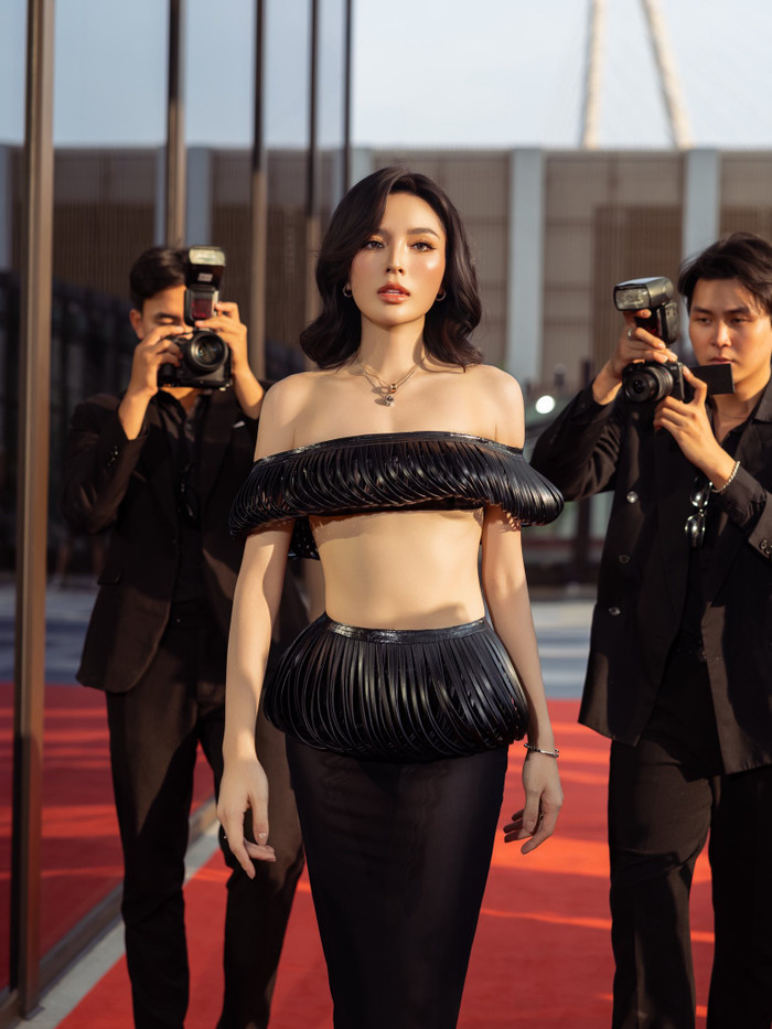 Hoa hậu Kỳ Duyên ại theo đuổi phong cách hiện đại với bộ trang phục cắt xẻ táo bạo, tập trung vào những đường xếp nếp cầu kỳ chạy dọc thân áo. Chất liệu ánh nhẹ ôm trọn cơ thể, tạo nên tổng thể mềm mại nhưng đầy cuốn hút. Layout trang điểm tone nude cùng mái tóc uốn nhẹ mang đến hình ảnh thời thượng, phóng khoáng nhưng không kém phần thanh lịch. Ảnh: FBNV