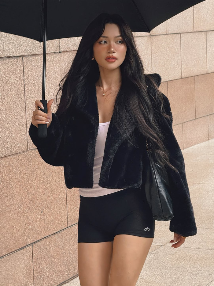 Những chiếc áo khoác lông ngắn tay, phối cùng tank top trắng và shorts đen, là lựa chọn quen thuộc khi Sĩ Thanh muốn mang đến vẻ ngoài street style ấm áp nhưng vẫn quyến rũ. Về phụ kiện, nữ ca sĩ thường mang túi xách da đen hoặc nâu, vòng tay vàng mảnh, và đôi khi là ô dù đen để hoàn thiện outfit, đặc biệt trong những ngày thời tiết thất thường. Ảnh: IGNV