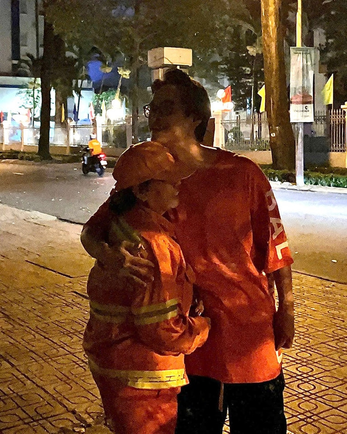 Hình ảnh Hà Anh Tuấn ôm động viên người phụ nữ quét đường khiến nhiều người xúc động. (Ảnh: FBNV)