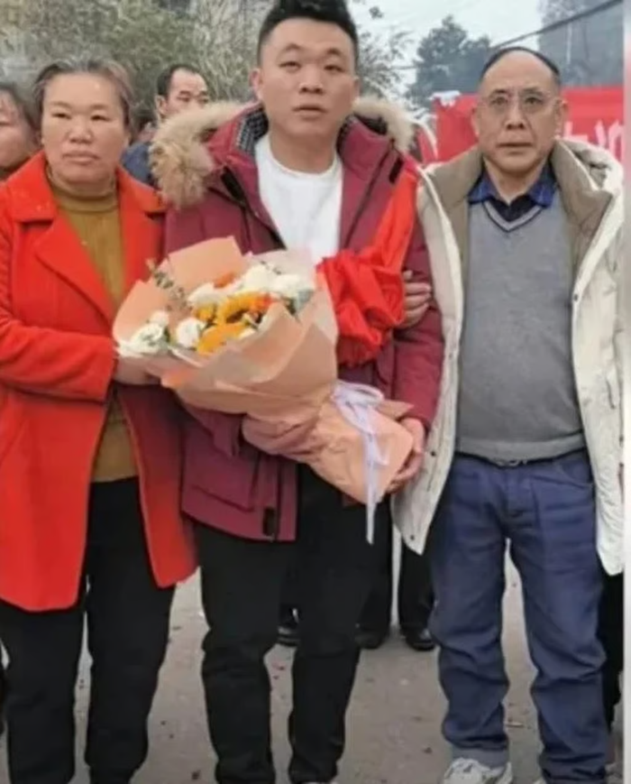 Peng Dingyi cầm hoa mừng khi chụp ảnh cùng cha mẹ ruột mới tìm thấy mình.