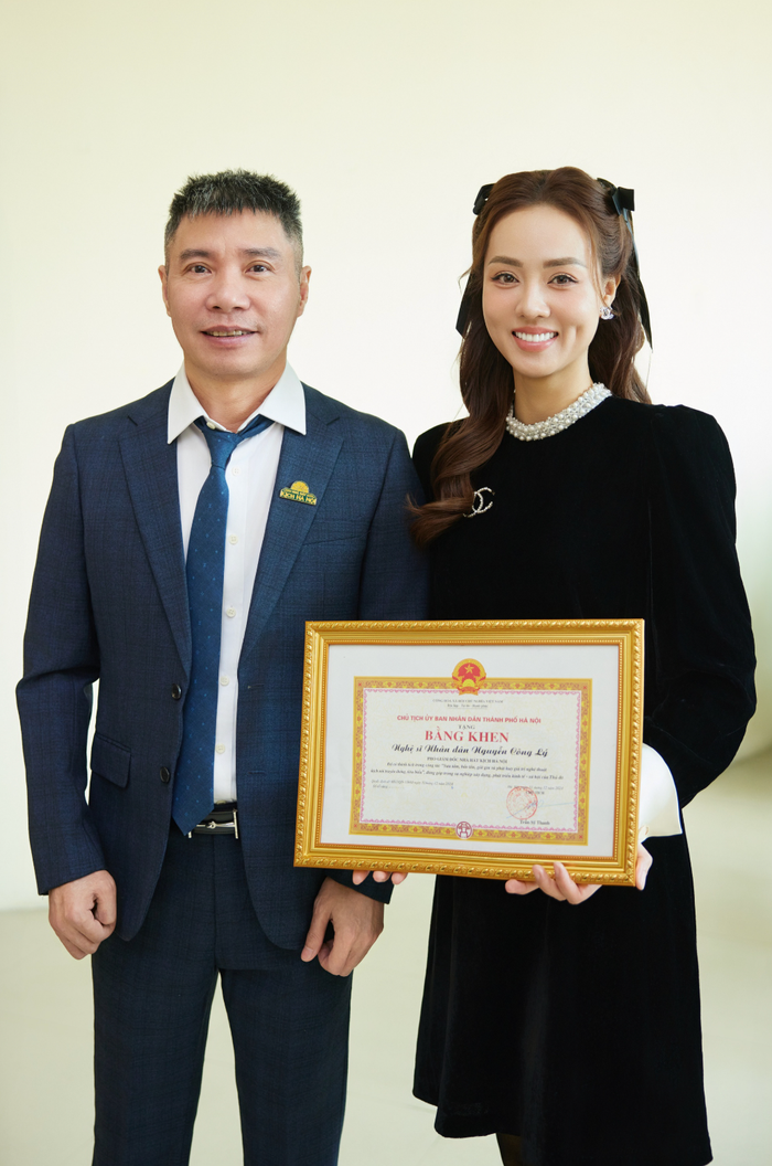 Công Lý diện vest lịch lãm cùng vợ nhận bằng khen hồi đầu năm nay. (Ảnh: Sưu tầm)
