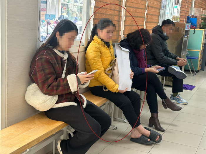 Chị H. (áo vàng) thẫn thờ ở hành lang bệnh viện trong lúc đợi chồng thăm khám. Ảnh: Dân Việt