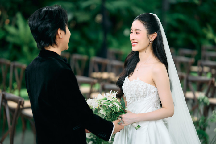 Cô dâu rạng rỡ tay cầm bó hoa cưới tươi tắn nắm tay Vũ Cát Tường. Gương mặt cô ánh lên niềm hạnh phúc, dịu dàng và tràn đầy yêu thương đánh dấu cho khoảnh khắc thiêng liêng trong chuyện tình của cả hai. 