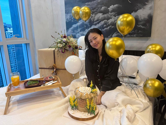 Ngô Thanh Vân hạnh phúc chụp ảnh với quà và bánh gato do chồng chuẩn bị. Ảnh: FBNV