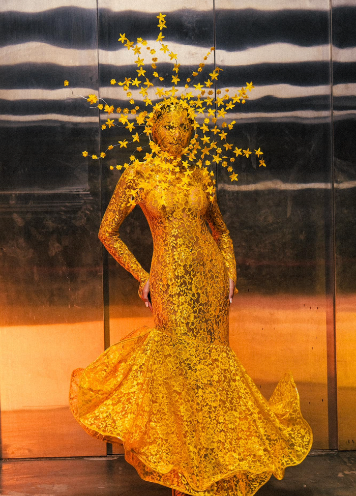 Một người đẹp khoác lên người bộ váy đuôi cá vàng óng, ôm sát vóc dáng. Thiết kế này được làm từ chất liệu xuyên thấu, tăng phần gợi cảm. Đặc biệt, điểm nhấn lớn nhất trong tạo hình của người đẹp này chính là phần mũ trùm kín mặt, đính kết nhiều dây hoa trông giống mặt trời. (Ảnh: Miss Grand Thailand)