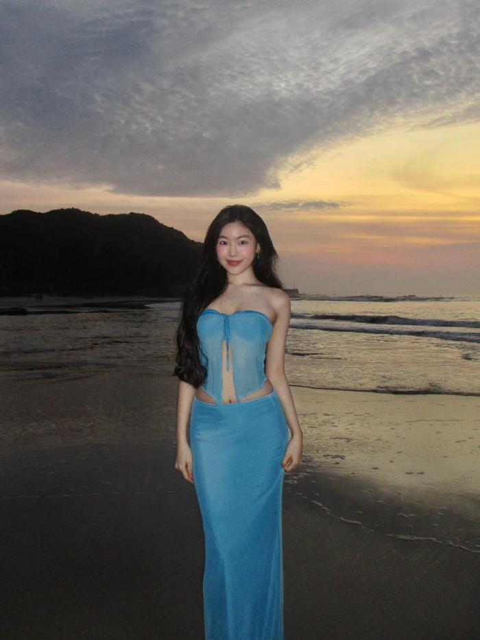 Mới đây, con gái Quyền Linh tiếp tục gây sốt khi khoe dáng với chiếc váy xanh dương mỏng nhẹ trong chuyến du lịch. Trang phục được may từ chất liệu voan mỏng nhẹ, mang lại cảm giác bồng bềnh và mềm mại, phù hợp hoàn hảo với khung cảnh lãng mạn của hoàng hôn trên biển.