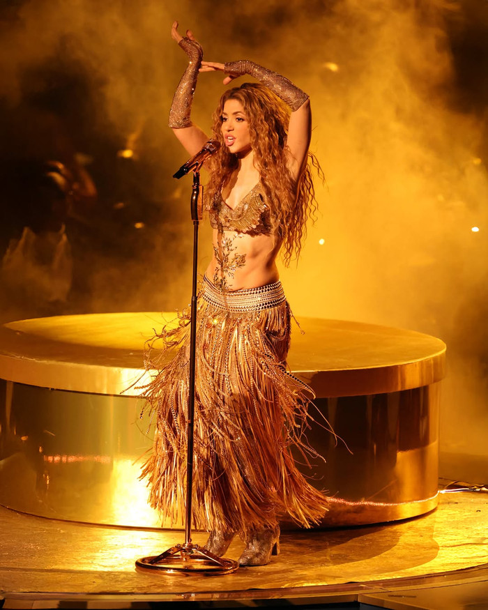 Shakira tái xuất sân khấu lễ trao giải Grammy sau 18 năm. Nhân dịp đặc biệt này, nữ ca sĩ khiến người hâm mộ được phen mãn nhãn với bữa tiệc âm nhạc hoành tráng với loạt bản hit cùng thời trang bắt mắt. Shakira 'lăng xê' phong cách 'bling bling' với bản phối gồm áo ngắn tựa bra cùng chiếc quần legging cùng màu vàng đồng và được làm từ chất liệu sequin lấp lánh. Không những vậy, chiếc quần legging của Shakira còn đính chi tiết tua rua dày đặc, tạo chuyển động khi trình diễn. Với màn 'lên đồ' này, nữ ca sĩ khoe khéo đôi 'gò bồng đào' đẫy đà cùng vòng eo phẳng lỳ, săn chắc. (Ảnh: Getty Images)